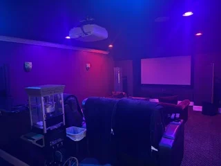 Entertainment room with purple and pink LED accent lighting, recessed ceiling fixtures, and wall-mounted RGB lighting system