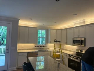 Kitchen with recessed ceiling lights and under-cabinet LED lighting installed above white cabinetry