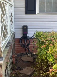 Black wall-mounted EV charger on brick exterior with weatherproof installation