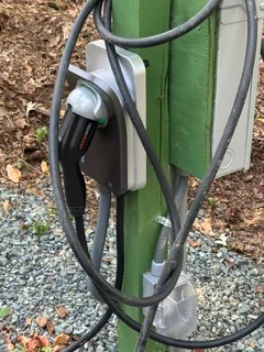 Wall-mounted EV charger with green housing and organized black cable management system