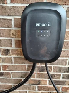 Black Emporia EV charger mounted on brick wall with cable management