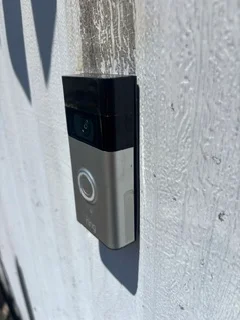 Video doorbell with camera installed on white stucco exterior wall