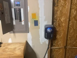 Electrical panel installation with circuit breaker box, outlet boxes, and wiring in drywall