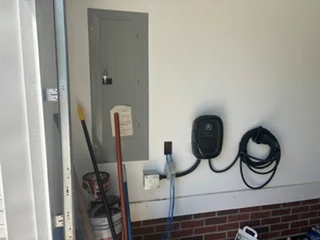 Electrical panel with conduit, outlets, and organized wiring on brick wall